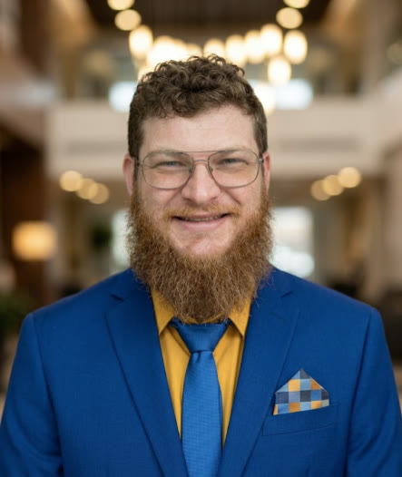 Jacob Sager, smiling, in glasses and a blue jacket